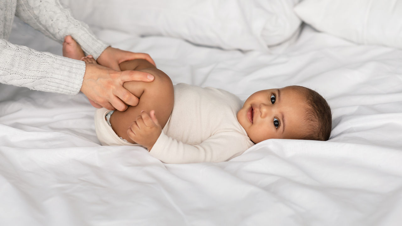 Mutter hält die Beine des Babys im Bett 