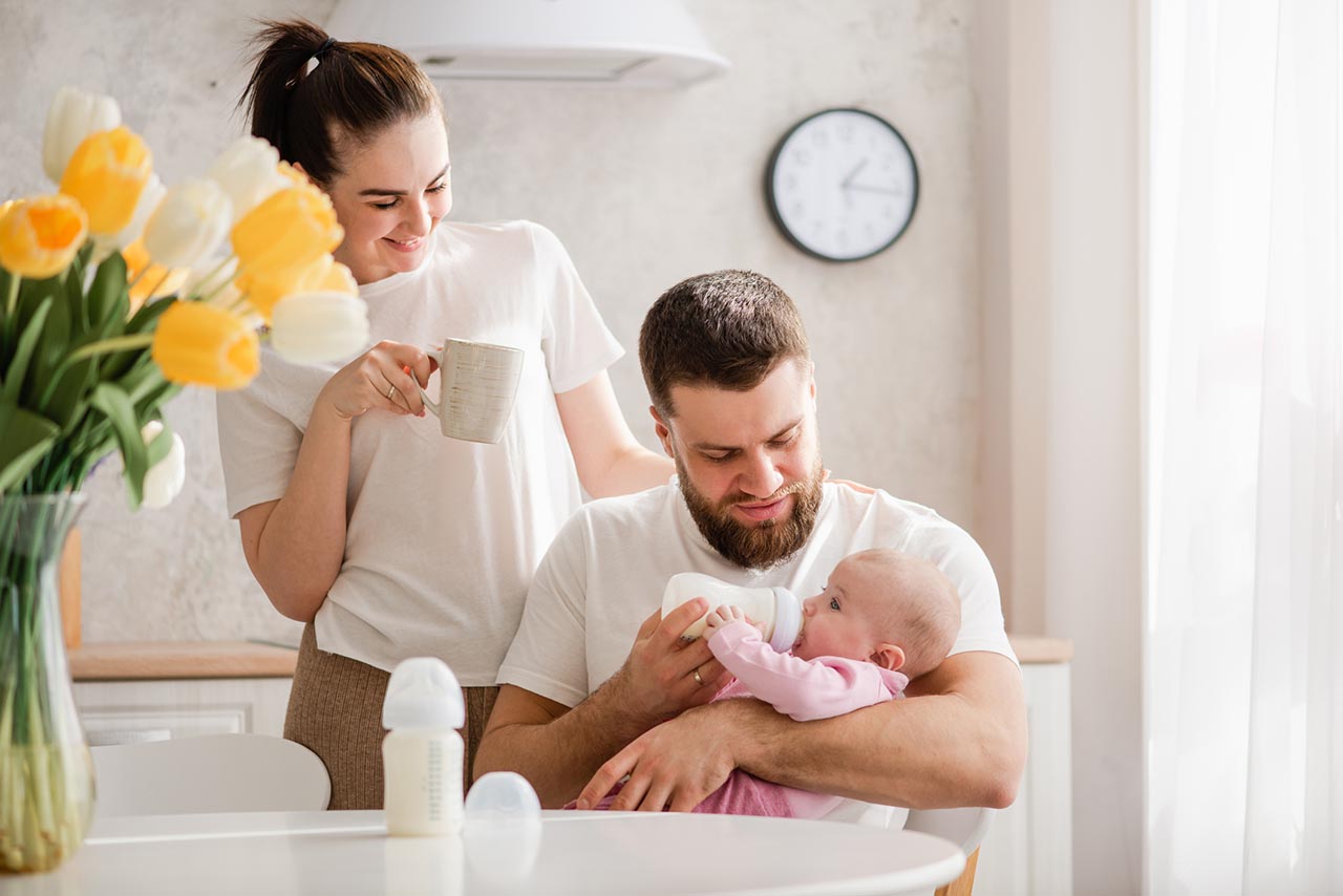 Baby wird vom Papa mit der Flasche gefüttert.