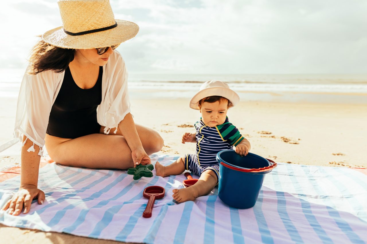 Mutter und Baby auf Stranddecke