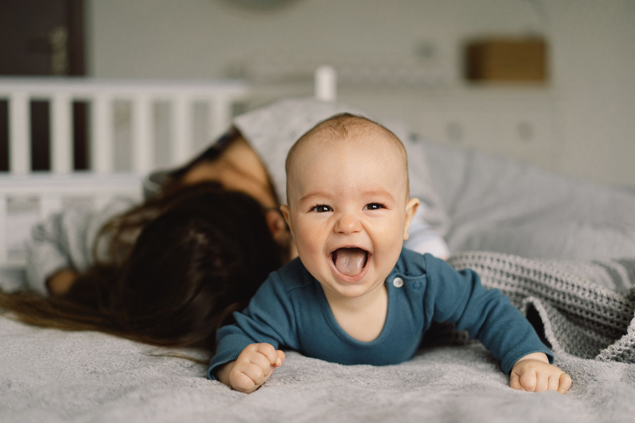 Mother and laughing baby in bed