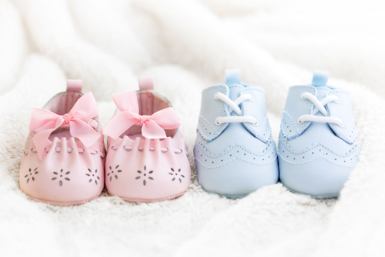 Babyschuhe in rosa und hellblau auf einer weißen Decke.