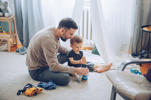 Father and baby son playing on floor with toys, they love to spend time together