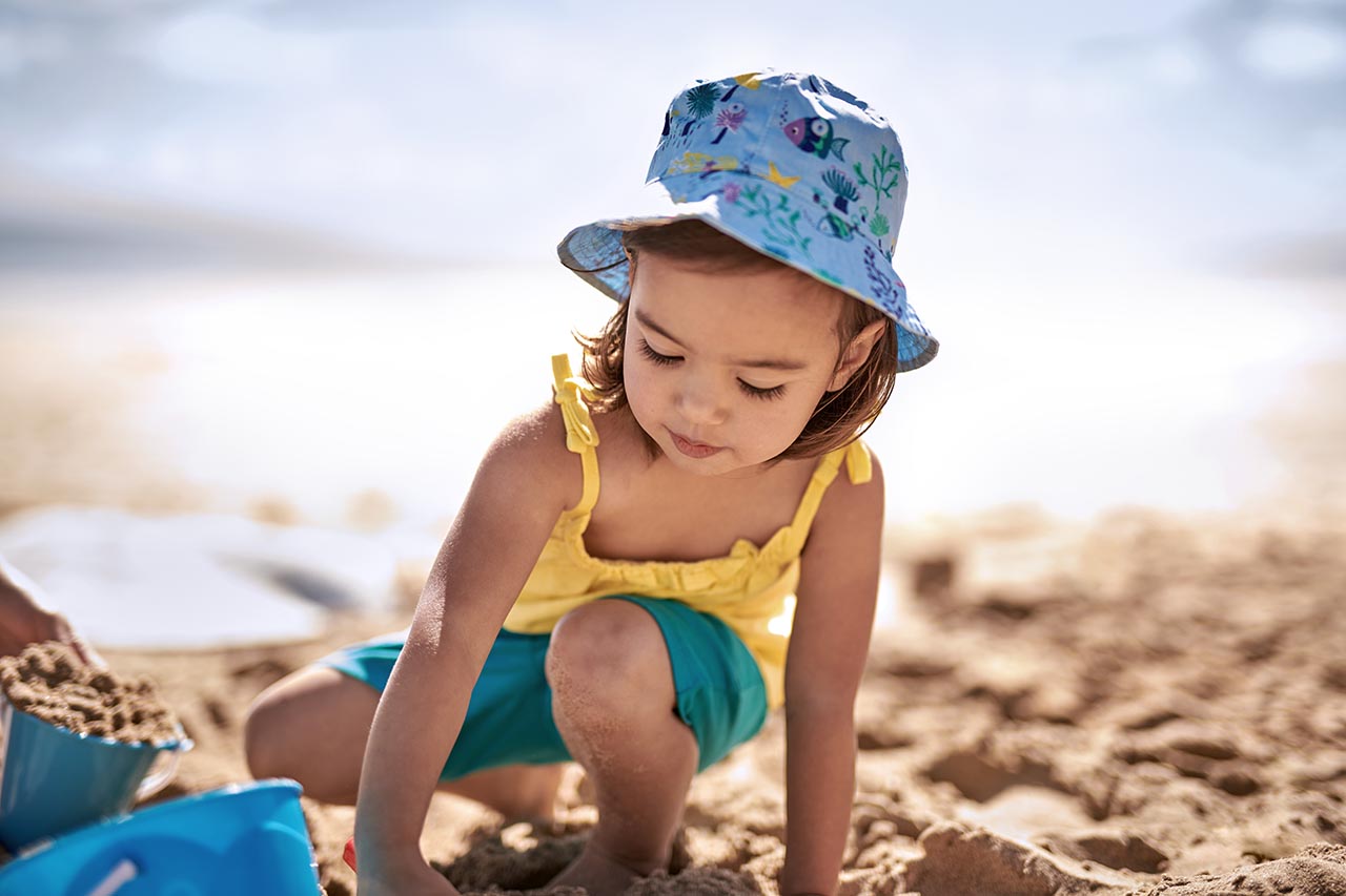 Kleinkind spielt am Strand im Sand.