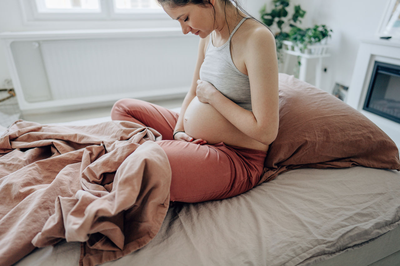 Schwangere sitzend hält ihren Bauch